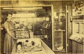 Historical photo of a woman holding up a display case while standing in a museum